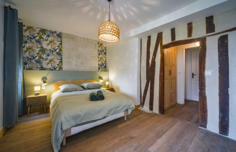 Luminoso dormitorio con cama de matrimonio, pared decorada y elementos de madera.