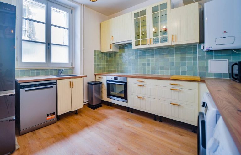 Cocina moderna con gabinetes amarillos, azulejos verdes y electrodomésticos integrados.