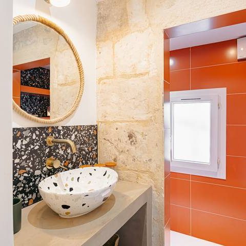 Salle de bains moderne avec évier en pierre et murs aux teintes orange et beige.