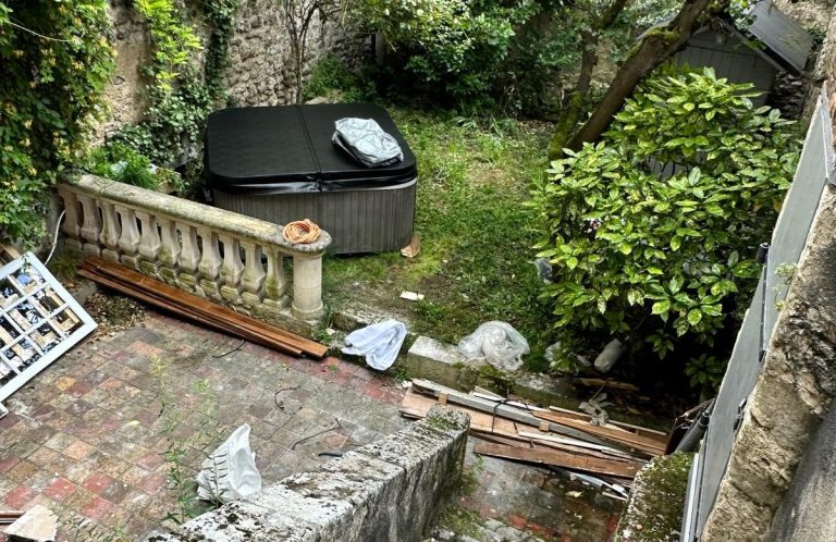Terraza con spa, escombros y plantas verdes alrededor.