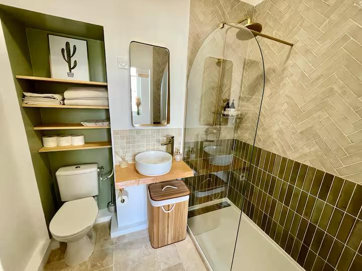 Salle de bain moderne avec douche, toilettes, lavabo sur meuble en bois et étagères.